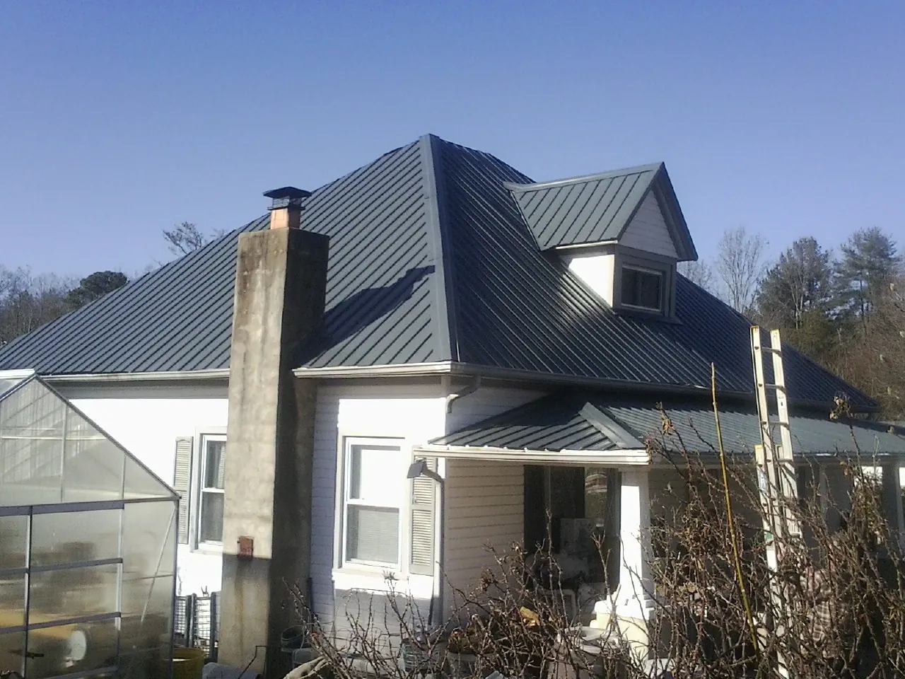 Dark blue standing seam metal roof on a white farmhouse with dormer — Slate & Tile Roof Repair by Roofing Brothers in Union Point