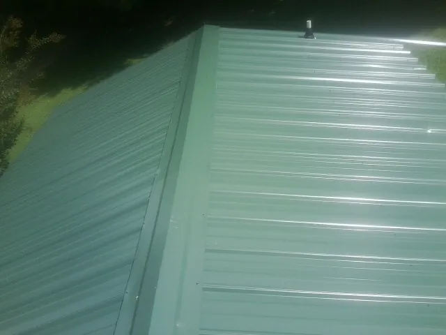New green metal panels meeting at the ridge of a roof — Flat Roof Repair work by our crew in Union Point