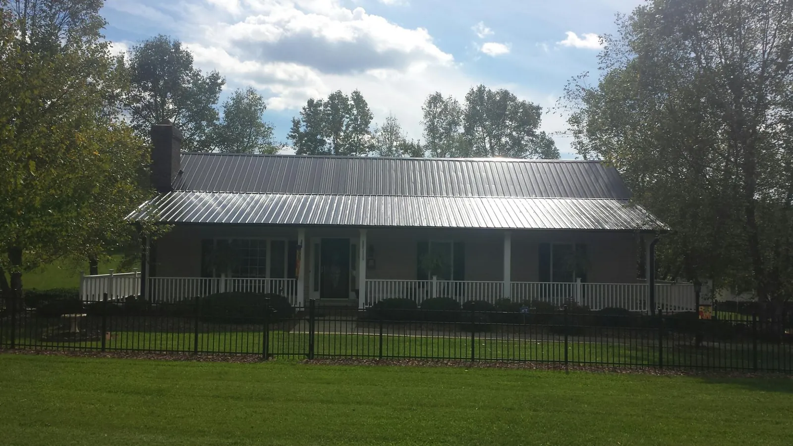 Gray metal roof on a brick ranch with a full width front porch — Gutter Guard Installation work by our crew in Union Point