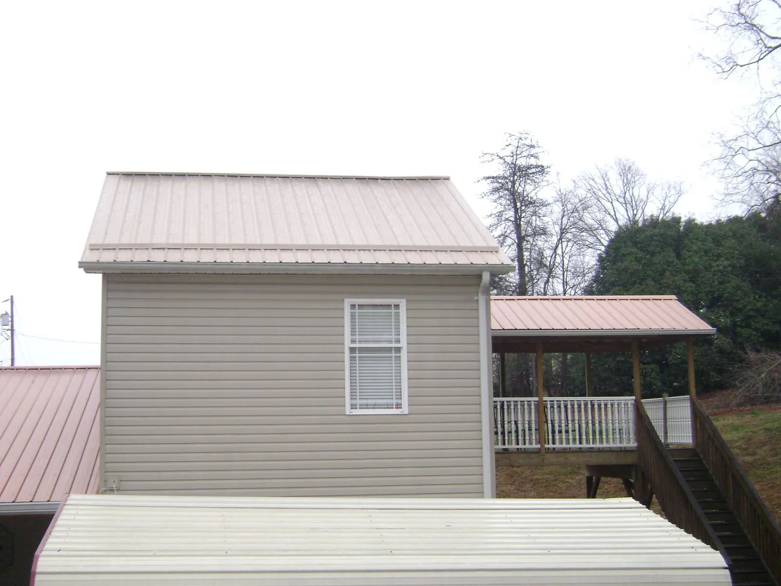 Tan metal roofs on a two story addition and attached porch, from a Roof Replacement job in Union Point