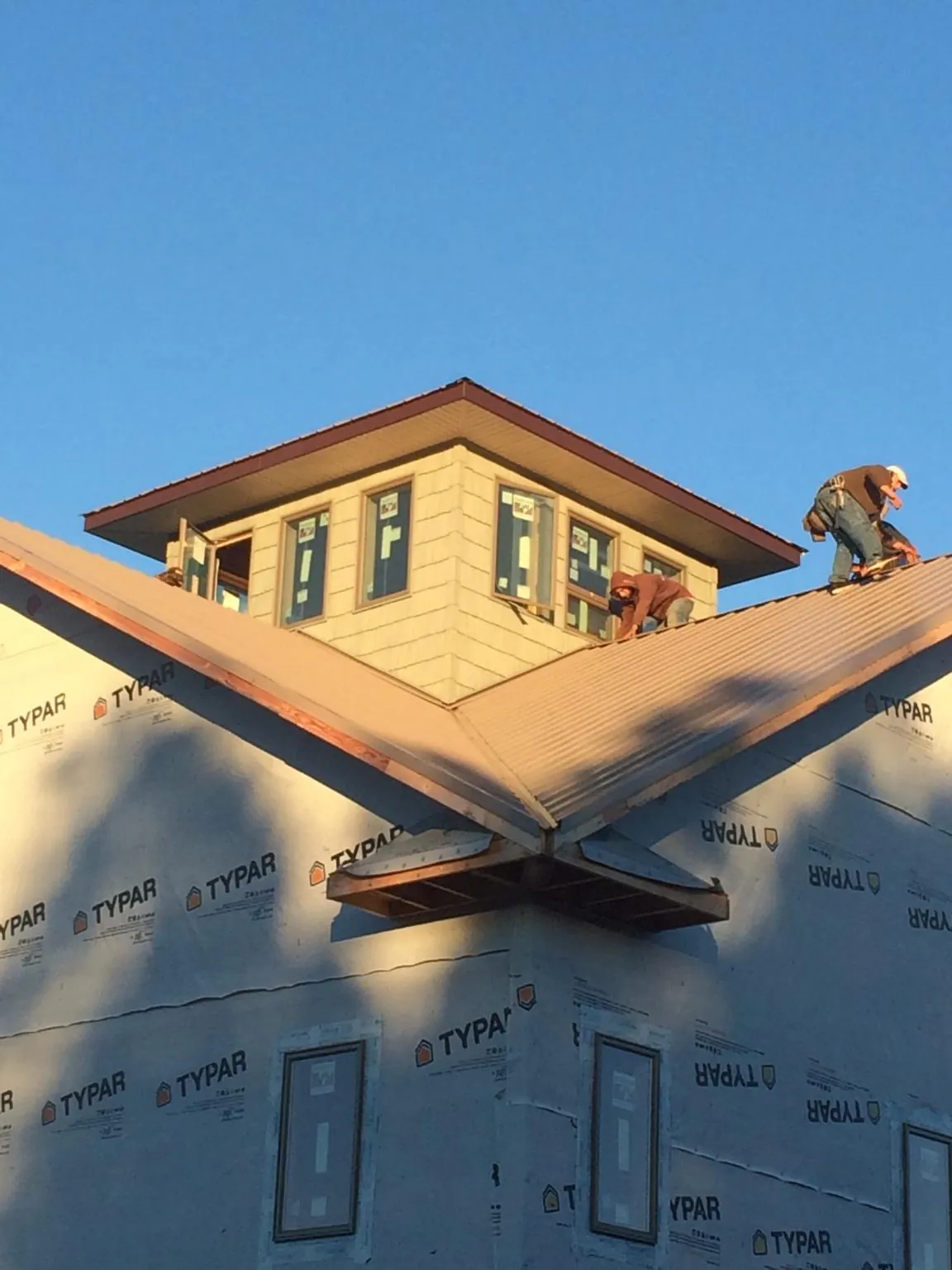 Roofers working around a rooftop cupola on a new metal roof at sunset — Roof Waterproofing in Union Point by Roofing Brothers